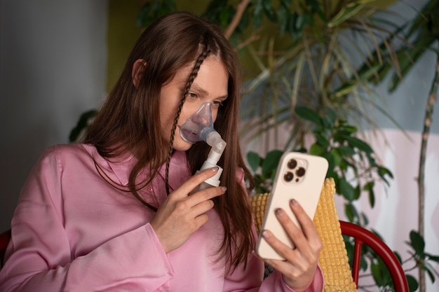 Foto gratuita donna del colpo medio che usa il nebulizzatore a casa