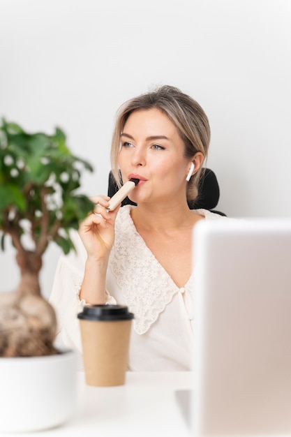 medium shot woman vaping at desk