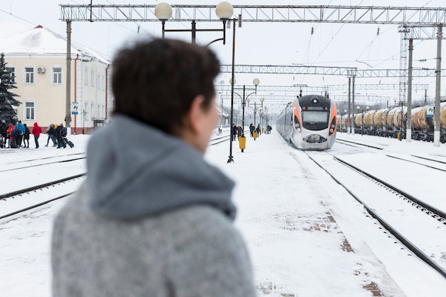 Женщина среднего роста ждет поезд