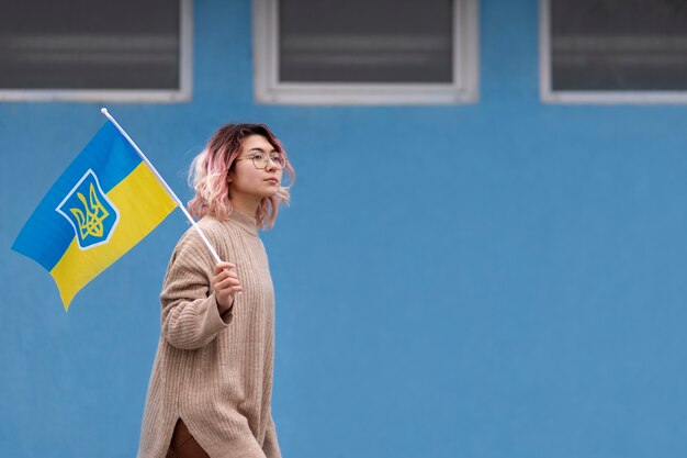 Medium shot woman walking with ukrainian flag