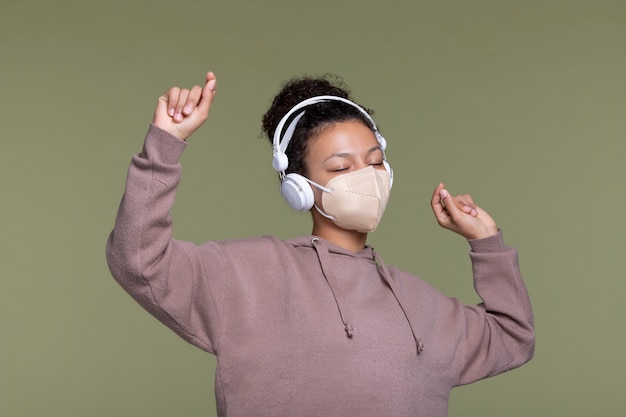 Foto gratuita donna di tiro medio che indossa maschera e cuffie