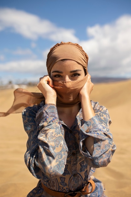 砂漠でスカーフを身に着けているミディアムショットの女性