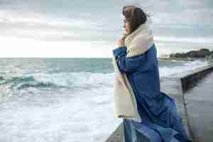 Free photo medium shot woman wearing scarf at seaside