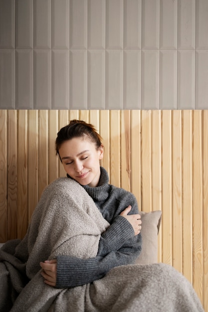 Medium shot woman with blanket at home