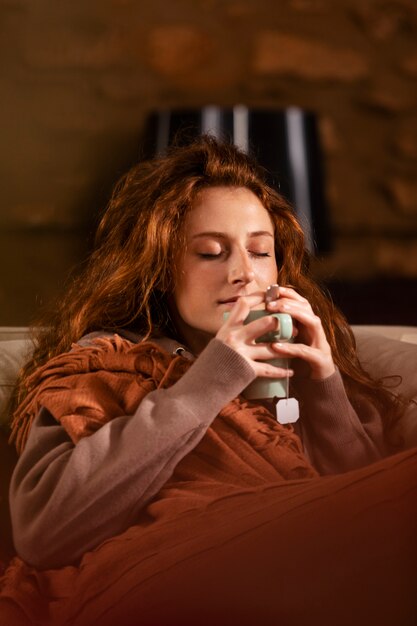 Medium shot woman with blanket and tea