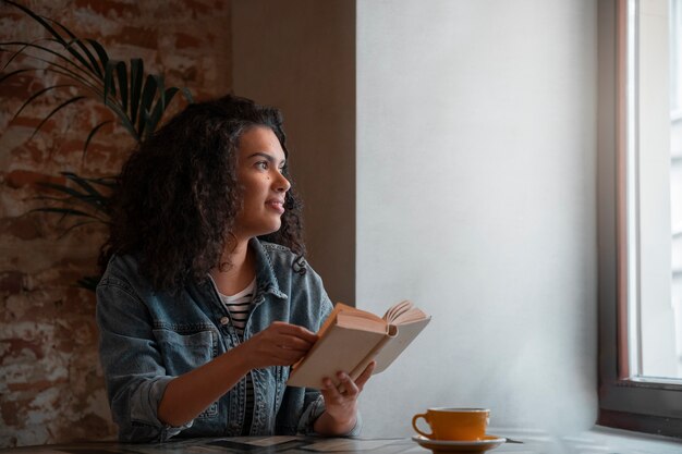 Medium shot woman with book in coffee shop