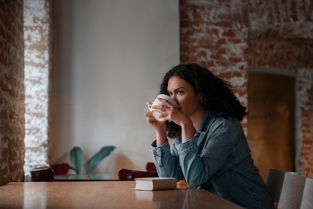 Free photo medium shot woman with book in coffee shop