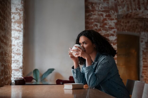 Medium shot woman with book in coffee shop