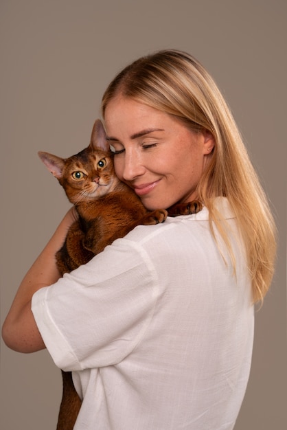 무료 사진 스튜디오에 고양이를 데리고 있는 중간 샷의 여자