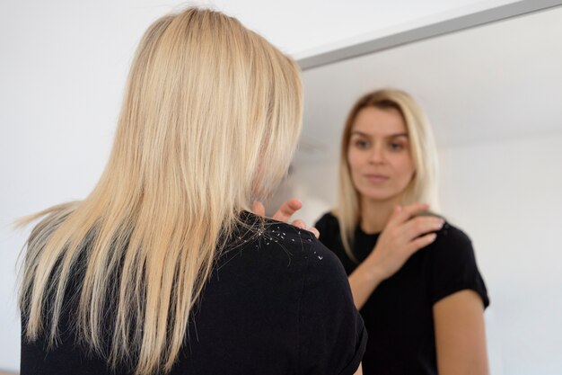 Medium shot woman with dandruff looking in mirror