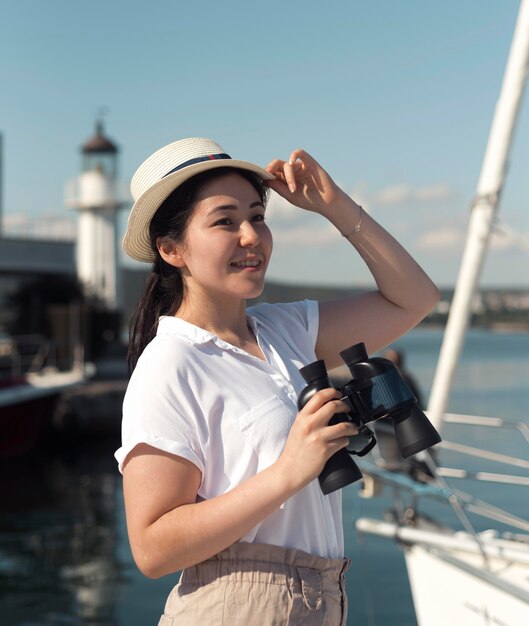 Medium shot woman with hat and binoculars