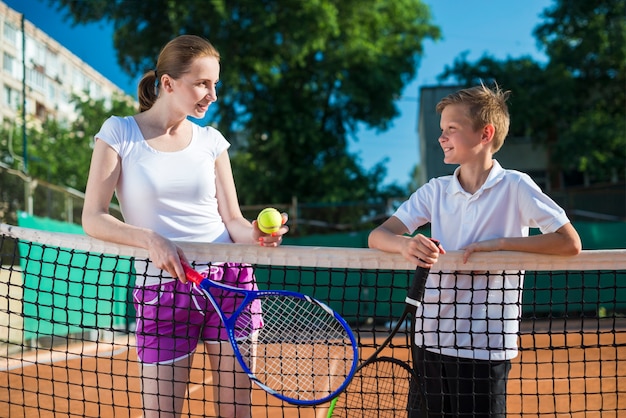 テニスをしている子供を持つミディアムショット女性