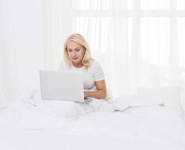 Medium shot woman with laptop in bed