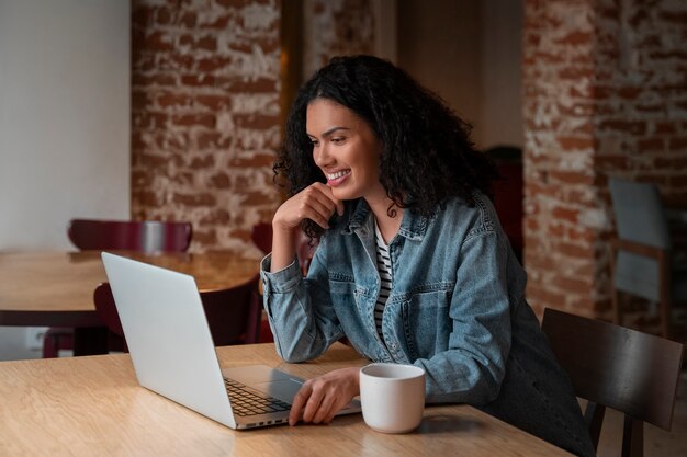 Medium shot woman with laptop in coffee shop