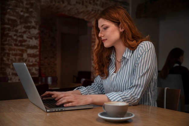 Free photo medium shot woman with laptop in coffee shop