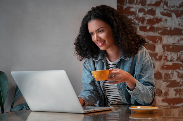 Medium shot woman with laptop in coffee shop