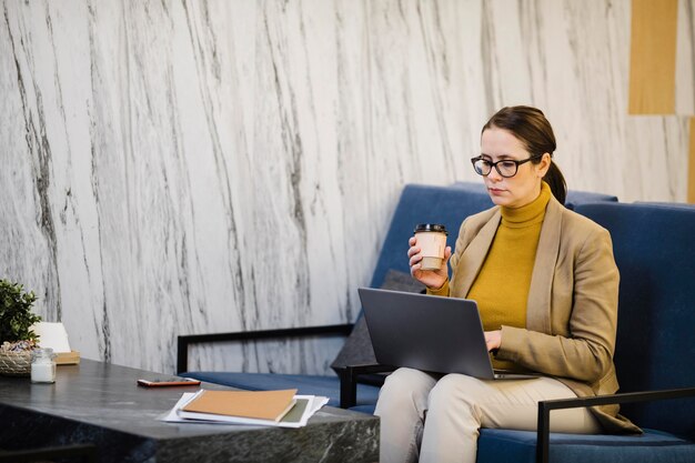 medium shot woman with laptop and cup