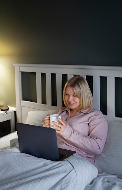 Foto gratuita donna del tiro medio con il computer portatile a casa