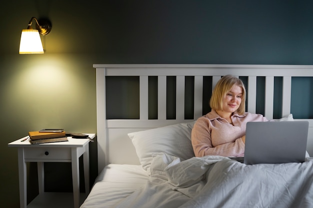 Foto gratuita donna del tiro medio con il computer portatile a casa