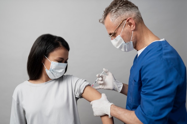 ワクチン接種を受けるマスクを持つミディアムショットの女性
