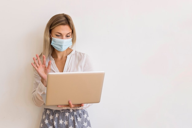 Medium shot woman with mask and laptop