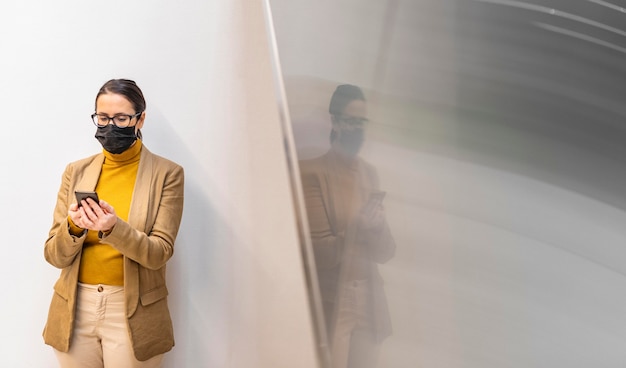 medium shot woman with mask and phone