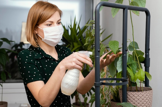 Free photo medium shot woman with mask watering plant