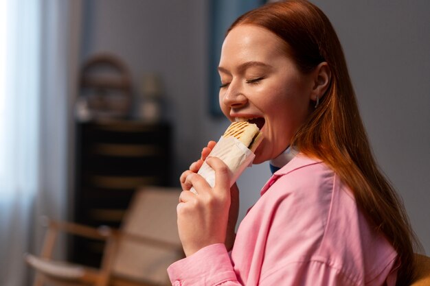 Medium shot woman with  paper-wrapped sandwich