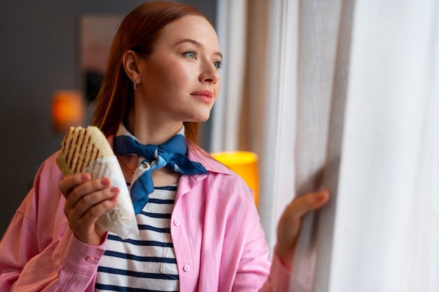 Free photo medium shot woman with  paper-wrapped sandwich