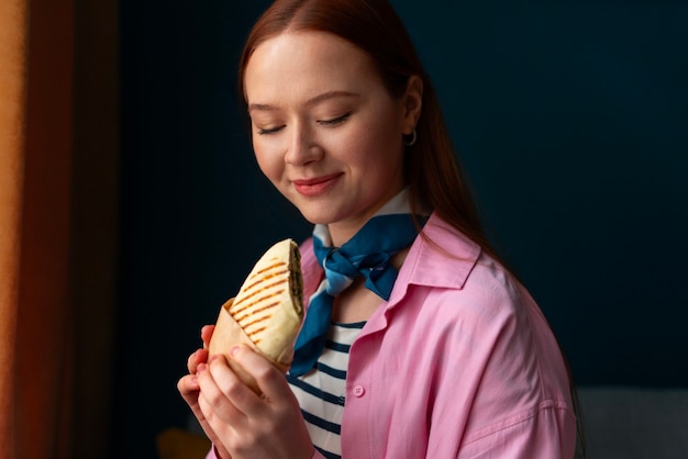 Free photo medium shot woman with  paper-wrapped sandwich