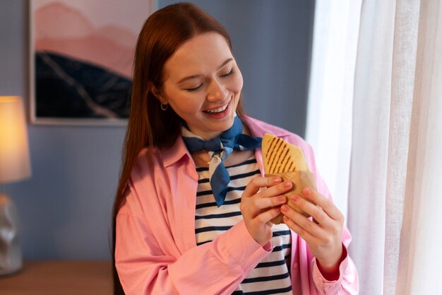 Medium shot woman with  paper-wrapped sandwich