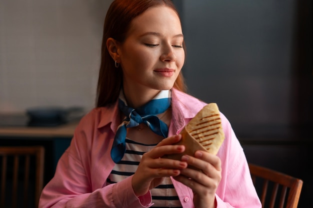 Free photo medium shot woman with  paper-wrapped sandwich