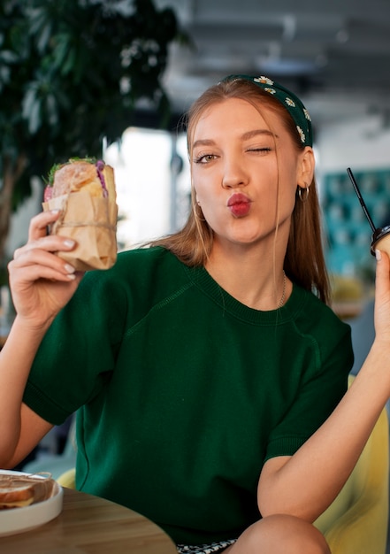 Free photo medium shot woman with paper-wrapped sandwich