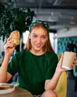 Free photo medium shot woman with paper-wrapped sandwich