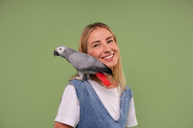 Medium shot woman with parrot in studio