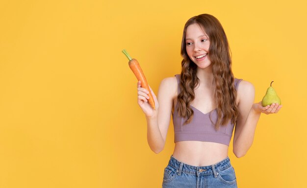 Medium shot woman with pear and carrot