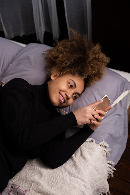 Medium shot woman with phone in bed