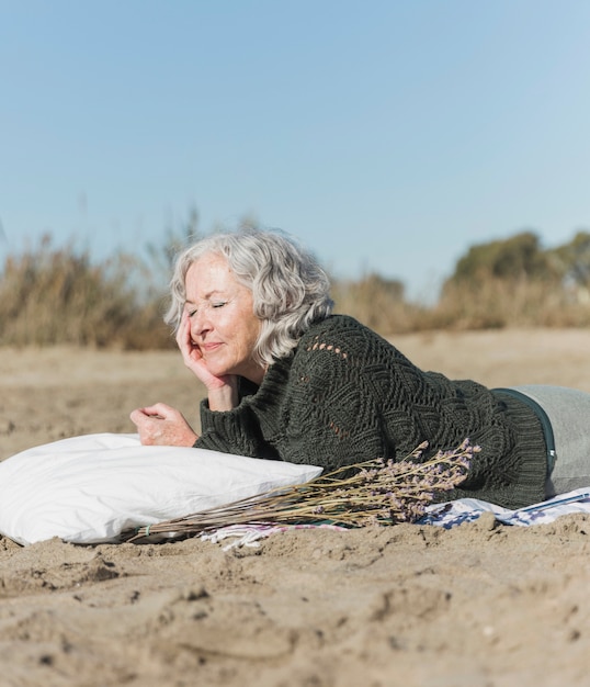 Colpo medio donna con cuscino sulla spiaggia