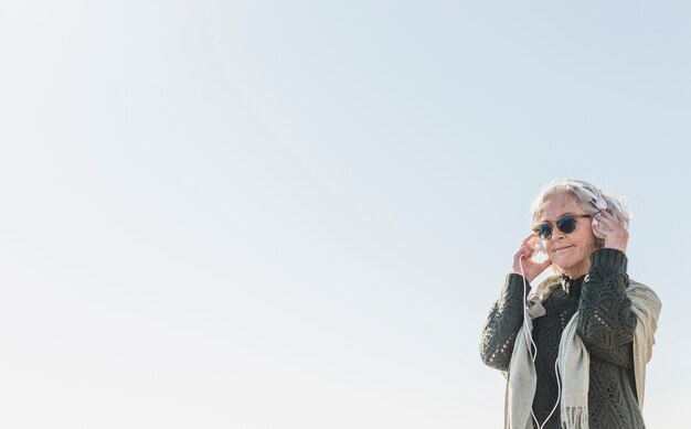 Medium shot woman with sunglasses and headphones