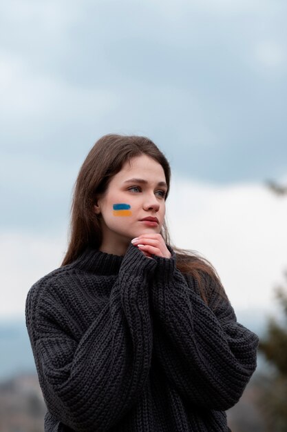 Medium shot woman with ukranian flag face drawing