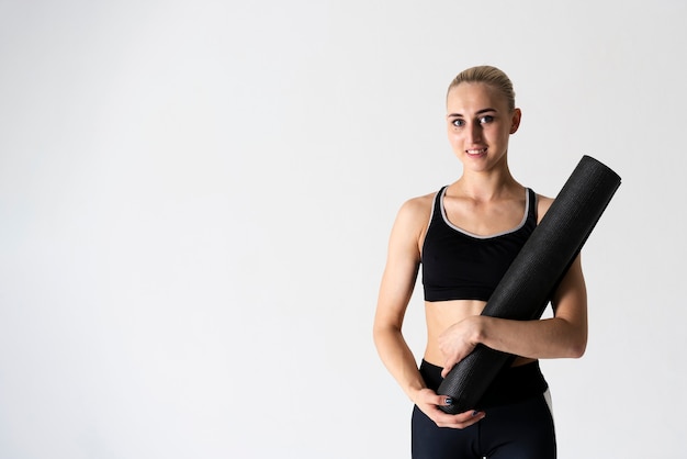 Medium shot woman with yoga mat and copy-space