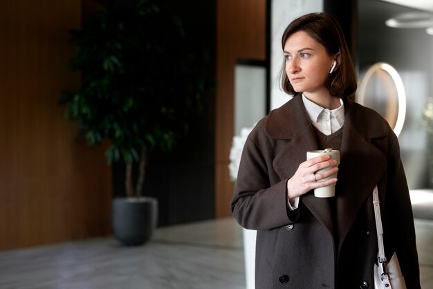 Foto gratuita donna del colpo medio al lavoro con una tazza di caffè