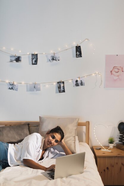 Medium-shot woman working on laptop in bed