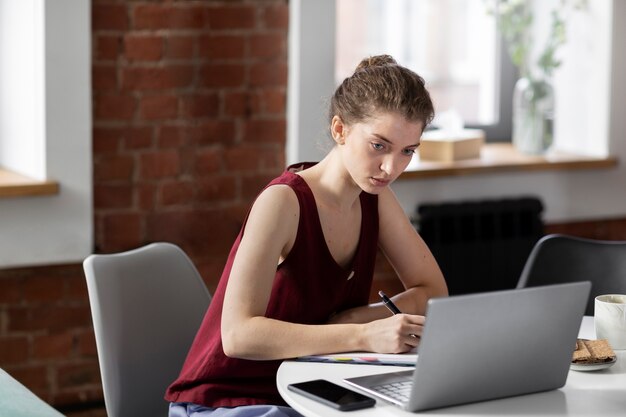 Medium shot woman working on laptop