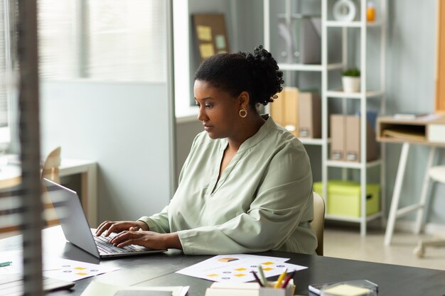 Medium shot woman working on laptop