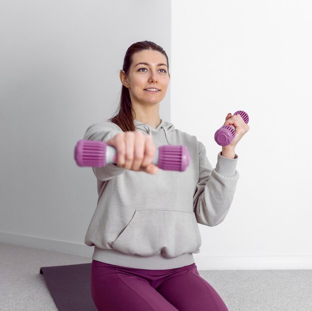 Foto gratuita donna del colpo medio che risolve con i manubri