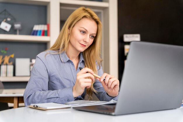 Medium shot woman working with laptop