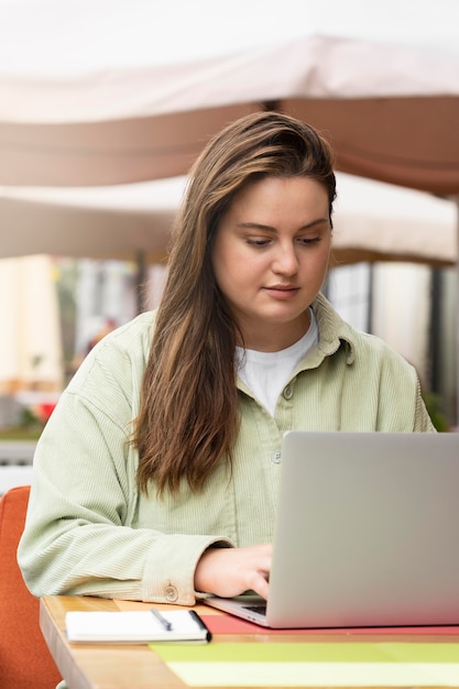 Medium shot woman working with laptop