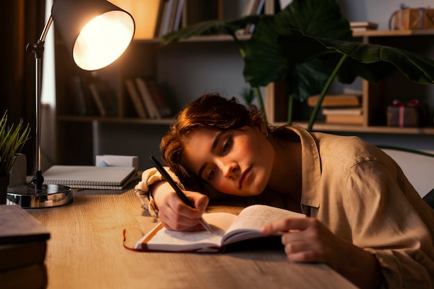 Foto gratuita donna del colpo medio che scrive nel suo diario