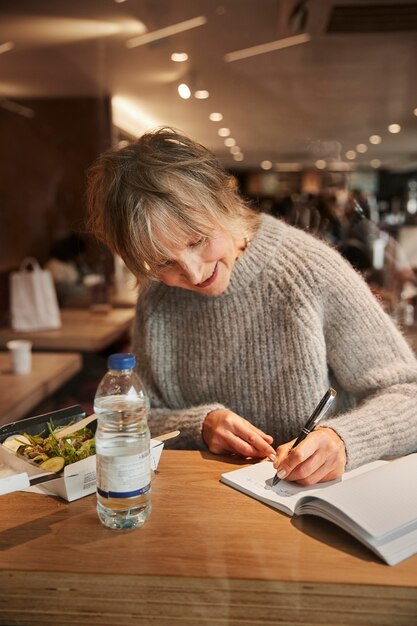 Medium shot woman writing on notebook